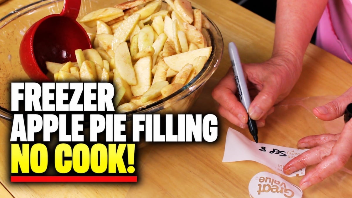 A person labels a bag while a bowl of sliced apples with a red ladle sits nearby. Text on the image reads: “Freezer apple pie filling. No cook!”.