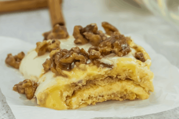 A layered pastry topped with icing and walnuts.