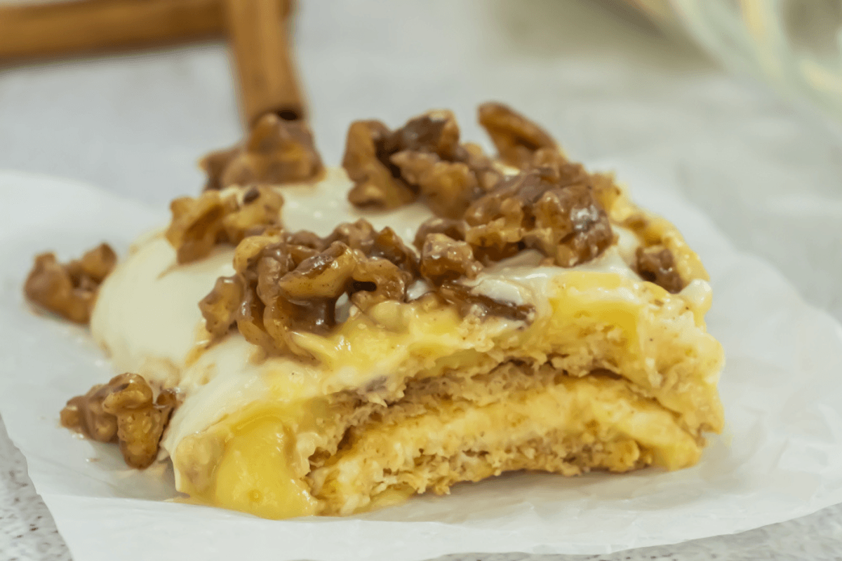 A layered pastry topped with icing and walnuts.